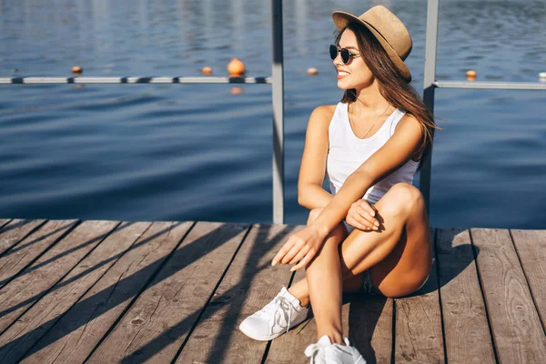 Schattig jong brunette meisje ontspannen op de pier in de buurt van meer. — Stockfoto