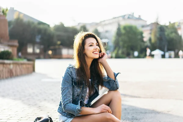 Mooie jonge glimlachende brunette meisje ontspannen buiten op de Stree — Stockfoto