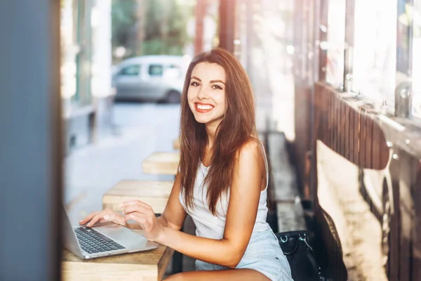 Hübsches junges Mädchen arbeitet auf Laptop in Straßencafé im Freien. — Stockfoto