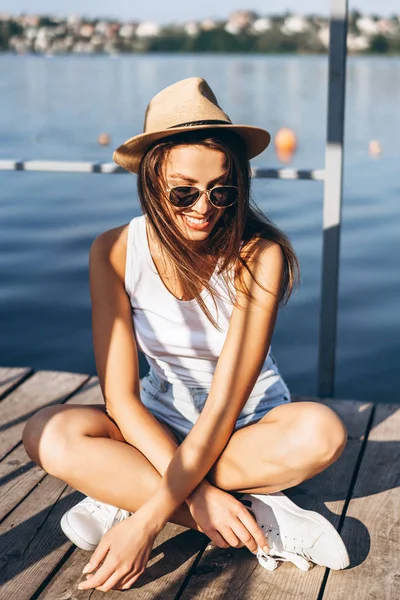 Schattig jong brunette meisje ontspannen op de pier in de buurt van meer. — Stockfoto