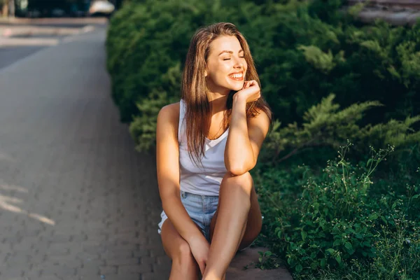 Jolie jeune fille brune souriante se relaxant en plein air sur le stree — Photo