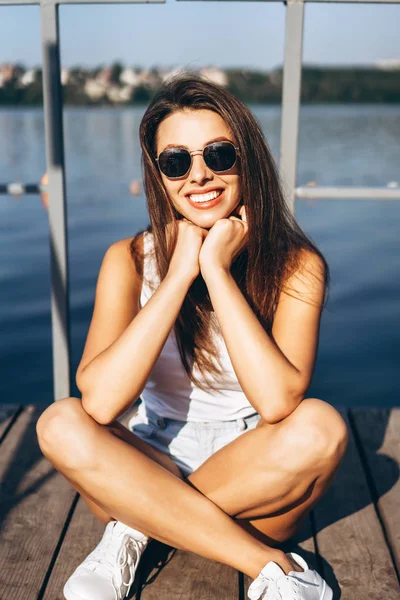 Cute young brunette girl relaxing on the pier near lake. — Stock Photo, Image