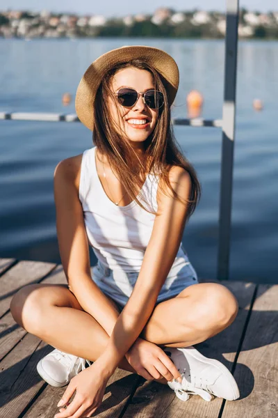 Schattig jong brunette meisje ontspannen op de pier in de buurt van meer. — Stockfoto