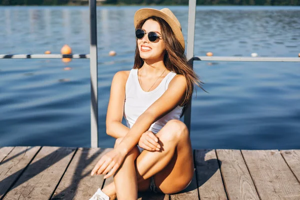 Carino giovane ragazza bruna rilassante sul molo vicino al lago . — Foto Stock