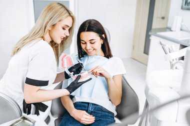 Protez üzerinde tedavi yolu açıklayan güzel kadın dişçi