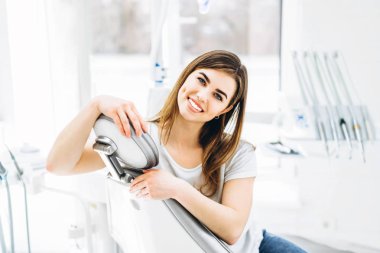 Dişinde oturan oldukça mutlu ve gülümseyen diş hastası