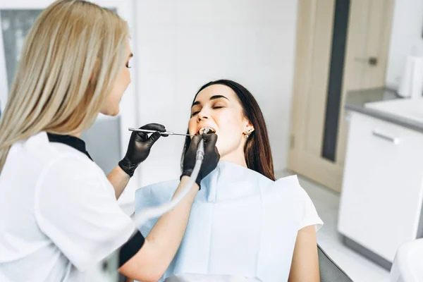 Pretty young female dentist making examination and treatment for — Stock Photo, Image