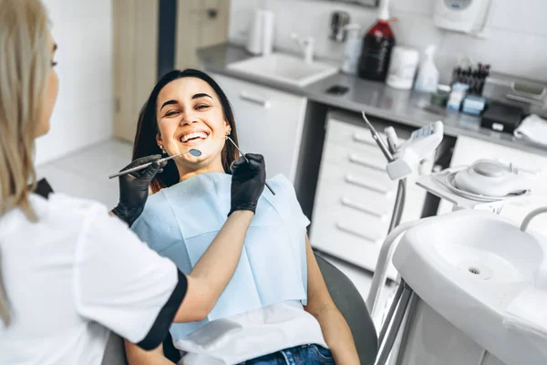 Pretty young female dentist making examination and treatment for — Stock Photo, Image