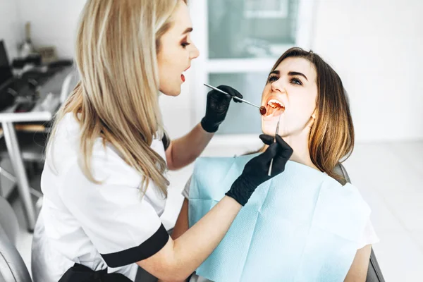 Pretty young female dentist making examination and treatment for — Stock Photo, Image