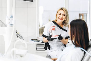 Protez üzerinde tedavi yolu açıklayan güzel kadın dişçi