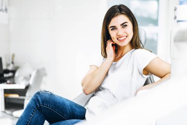 Dişinde oturan oldukça mutlu ve gülümseyen diş hastası