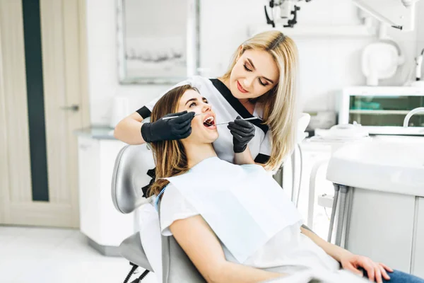 Pretty young female dentist making examination and treatment for — Stock Photo, Image