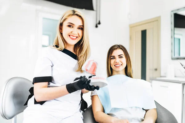 Protez üzerinde tedavi yolu açıklayan güzel kadın dişçi — Stok fotoğraf