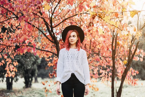 Vacker flicka med rött hår och hatt går i parken, höst ti — Stockfoto