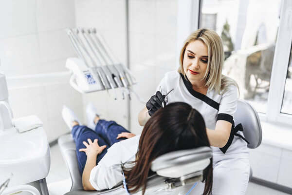 Прекрасная молодая женщина-стоматолог, проводящая обследование и лечение
