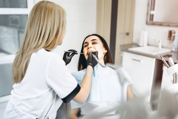 Pretty young female dentist making examination and treatment for — Stock Photo, Image