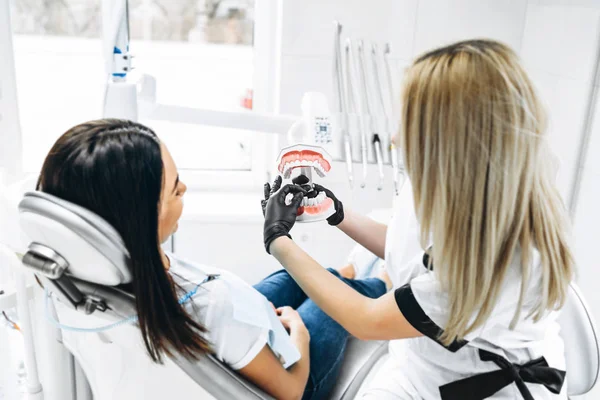 Dentista bastante femenina explicando la forma de tratamiento de la dentadura postiza — Foto de Stock