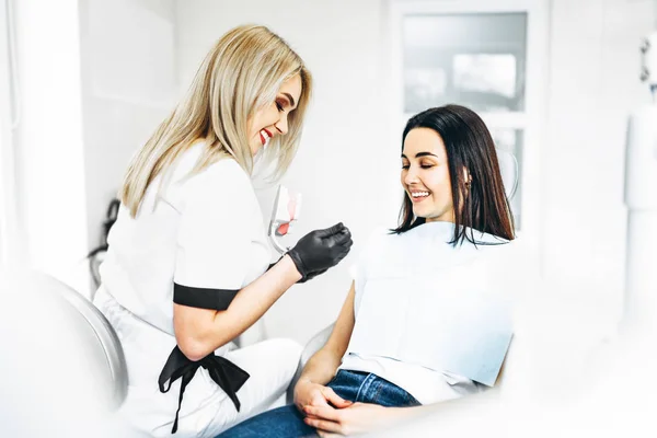 Dentista bastante femenina explicando la forma de tratamiento de la dentadura postiza —  Fotos de Stock