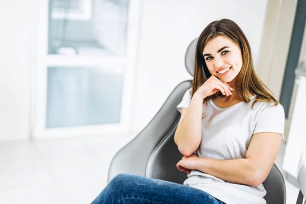 Pretty happy and smiling dental patient sitting in the dental ch — Stock Photo, Image