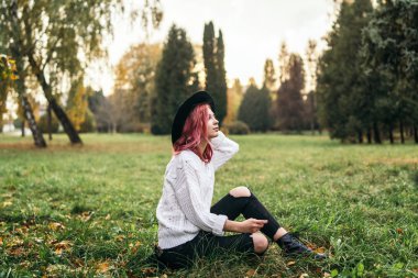 Parkta rahatlatıcı kırmızı saçlı ve şapka ile Pretty kız, sonbahar t