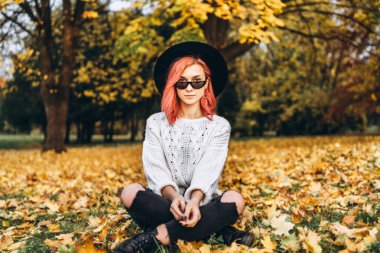 Parkta rahatlatıcı kırmızı saçlı ve şapka ile Pretty kız, sonbahar t