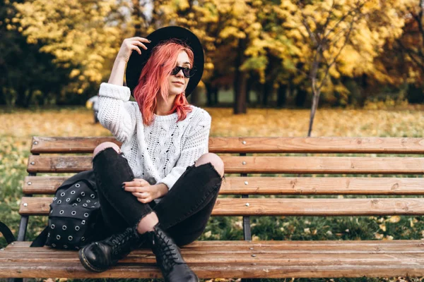 Menina bonita com cabelo vermelho e chapéu relaxante no banco no p — Fotografia de Stock