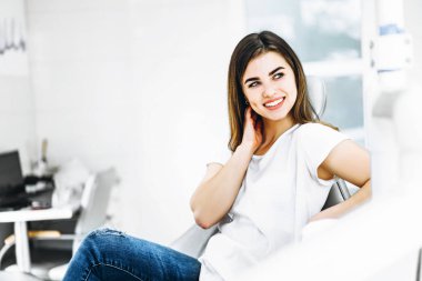 Dişinde oturan oldukça mutlu ve gülümseyen diş hastası