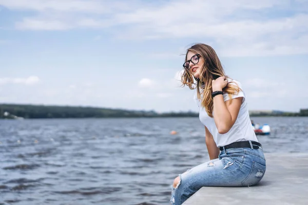 Mladá Žena Dlouhými Vlasy Stylových Brýlích Pózující Betonovém Břehu Jezera — Stock fotografie