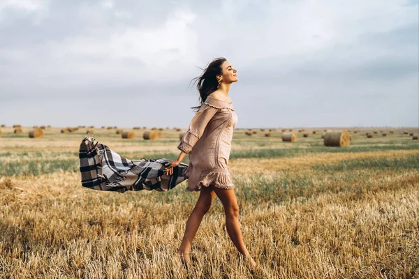全长肖像一个美丽的黑发在衣服和温暖的格子花 女人带着草袋在麦田里散步 — 图库照片