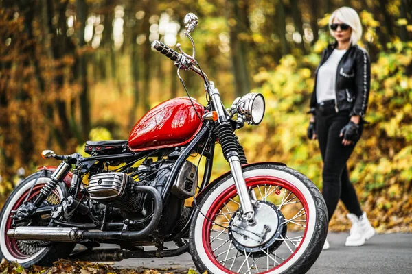 在森林的路上 一个戴着墨镜 戴着红色摩托车 背景五彩斑斓的漂亮金发骑自行车的女孩 — 图库照片