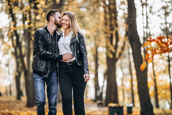 晴れた日には美しい若いカップルが秋の公園を歩いています 彼らは抱擁と笑顔 散歩を楽しむ — ストック写真