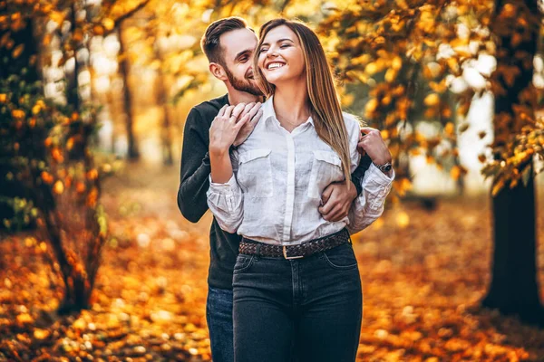 一对恋爱中的年轻夫妇在一个阳光灿烂的日子漫步在秋天的公园里 男人轻轻拥抱着女人 爱情故事 — 图库照片