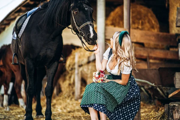 Ładna Blondynka Tradycyjnej Sukience Dba Wielkiego Czarnego Konia Farmie Koncepcja — Zdjęcie stockowe