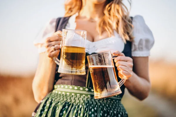 穿着传统节日服装的金发美女很开心 坐在户外 两杯啤酒 背景模糊 Oktoberfest Patricks Day International Beer Day — 图库照片