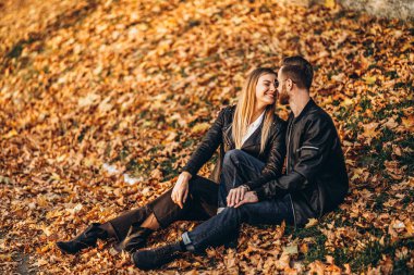 Sonbahar yaprağında oturan ve doğanın tadını çıkaran genç bir çiftin portresi. Aşk hikayesi..