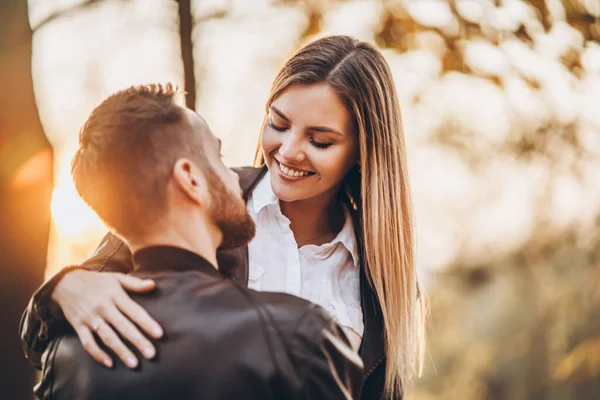 一对年轻夫妇在秋天公园的背景上接吻 一个男人把他的女人抱在怀里 — 图库照片