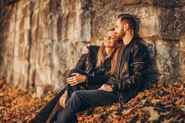 Genç Bir Çiftin Portresi Sonbahar Yaprağında Taş Duvarın Yanında Oturuyor — Stok fotoğraf