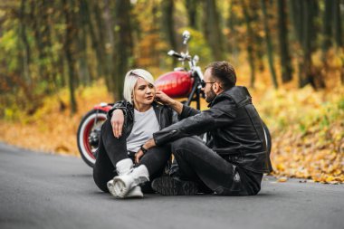 Ormanda kırmızı motosikletin yanında oturan güzel bir çift. Renkli, mavi bir geçmişi var. İlişkiler kavramı.