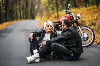 Ormanda kırmızı motosikletin yanında oturan güzel bir çift. Renkli, mavi bir geçmişi var. İlişkiler kavramı.