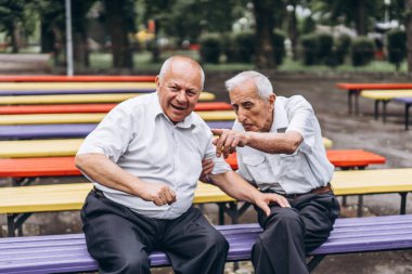 İki yaşlı yetişkin adam şehir parkında sohbet ediyor.