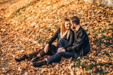Sonbahar yaprağında oturan ve doğanın tadını çıkaran genç bir çiftin portresi. Aşk hikayesi..