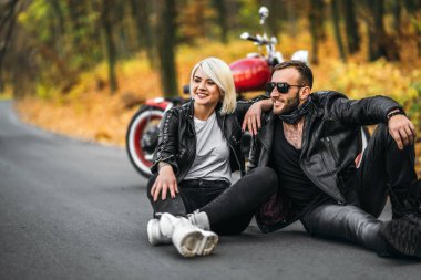 Ormanda kırmızı motosikletin yanında oturan güzel bir çift. Renkli, mavi bir geçmişi var. İlişkiler kavramı.