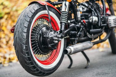 Kırmızı özel yapım, eski moda motosiklet ormanda yol kenarında. Renkli, bulanık bir arka planı var.
