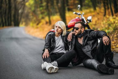 Ormanda kırmızı motosikletin yanında oturan güzel bir çift. Renkli, mavi bir geçmişi var. İlişkiler kavramı.