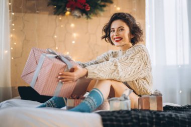 Yatağında hediye kutularıyla mutlu ve güzel bir esmer. Yeni yıl, Noel, doğum günü, Sevgililer Günü konsepti