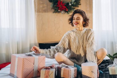 Yatağında hediye kutularıyla mutlu ve güzel bir esmer. Yeni yıl, Noel, doğum günü, Sevgililer Günü konsepti