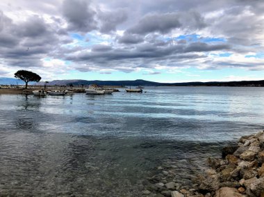 Deniz kıyısındaki insanlar güzel bir günbatımının arka planına karşı. Sonsuz ufka bakan sahil manzarası