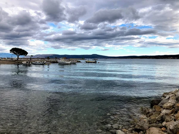 Deniz kıyısındaki insanlar güzel bir günbatımının arka planına karşı. Sonsuz ufka bakan sahil manzarası