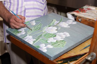 Sanatçı bir natürmort çiçek ile boyama yaparken elleri. Moskova. 07.08.2016