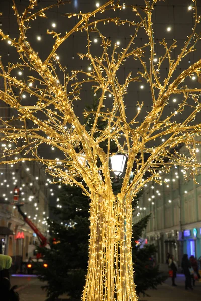 Street decorations, luminous Golden tree on the background of houses
